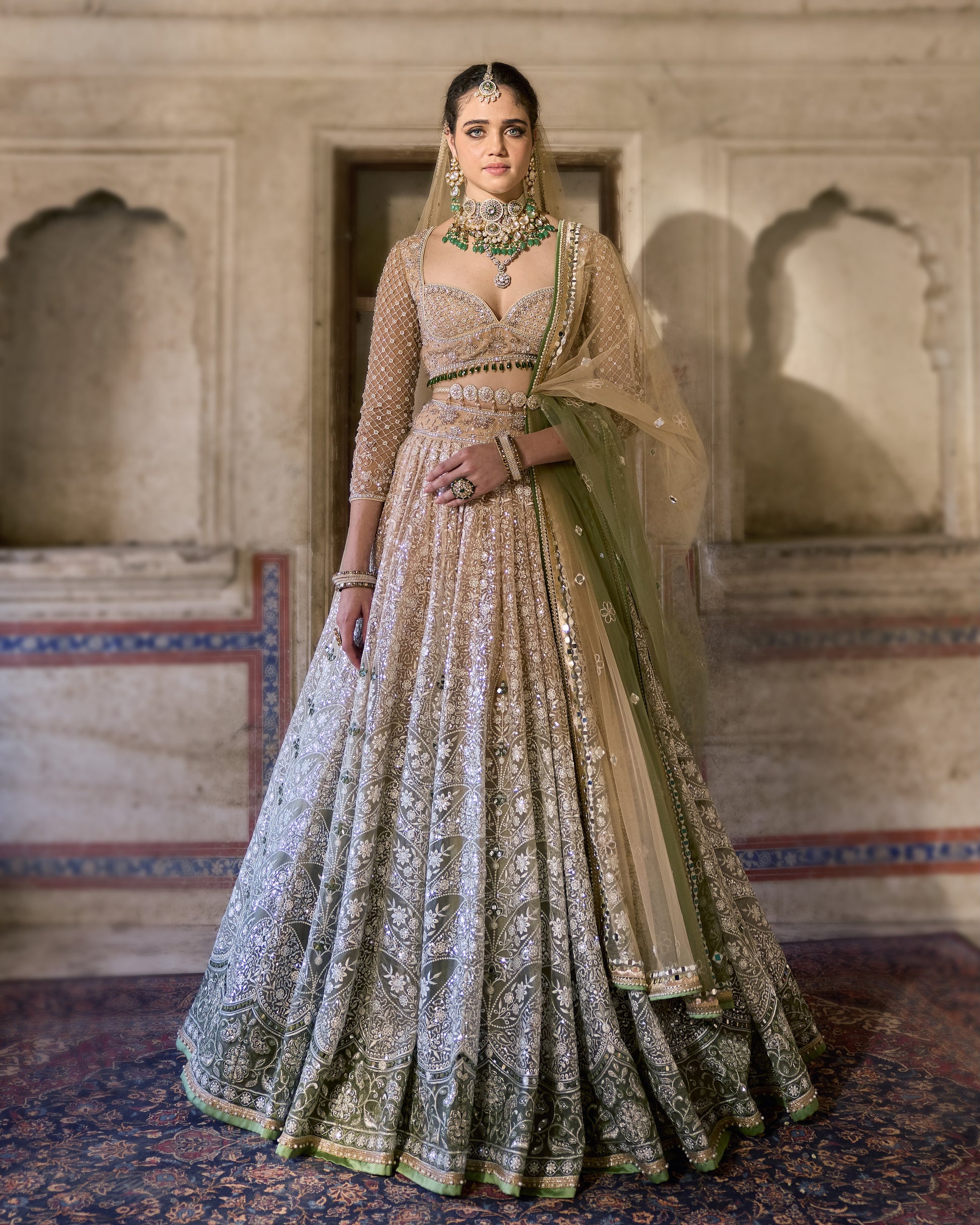 Model wearing ivory organza lehenga with sage green embroidery – front view