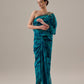 Woman wearing a teal one-shoulder dress against a plain background