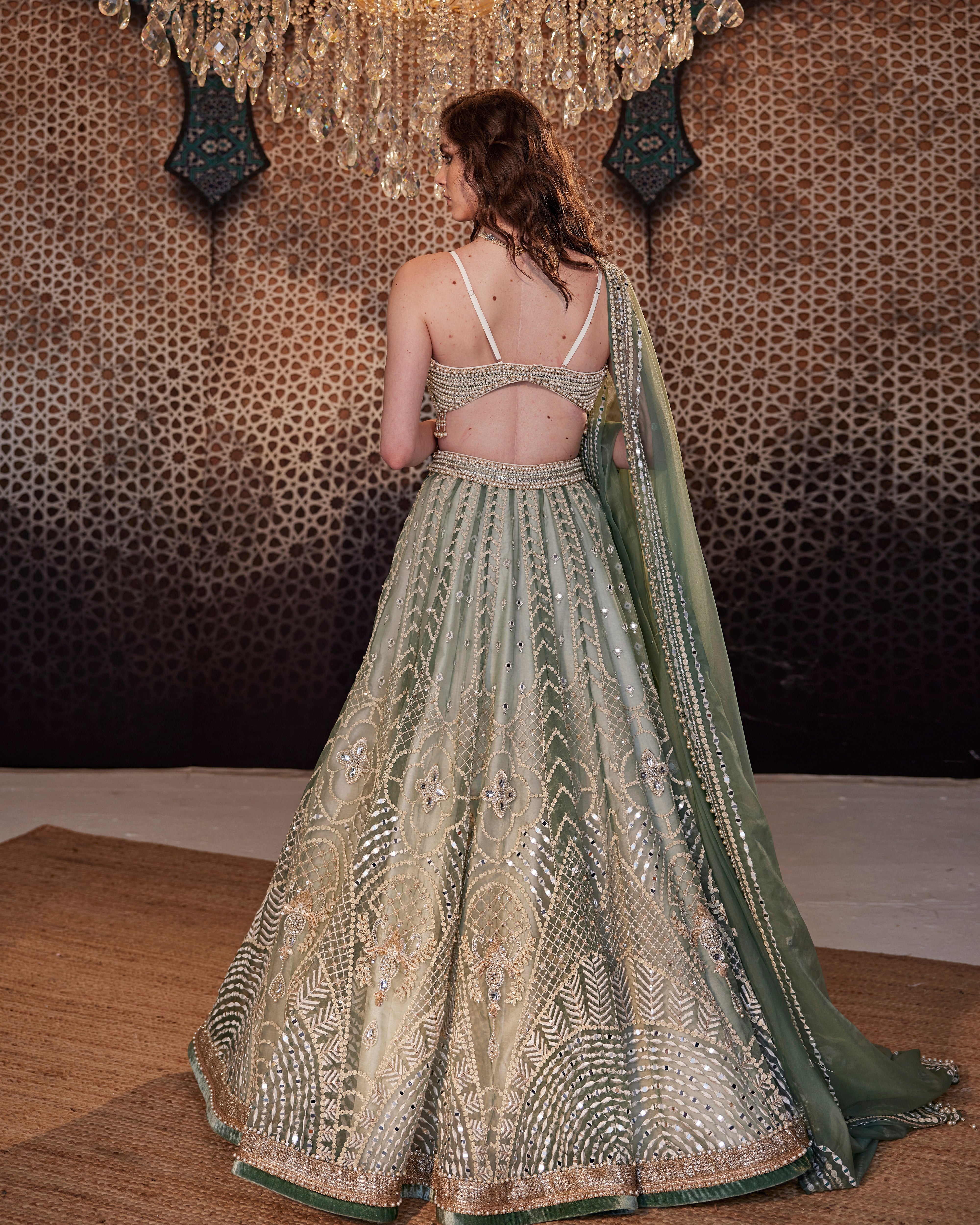 An english green paneled raw silk handcrafted lehenga teamed with blouse  and contrast tulle dupatta. . 